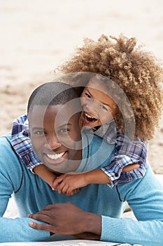 Father and son playing piggyback on beach