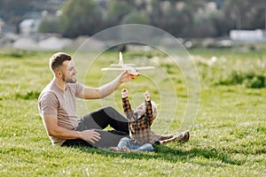 Father and son playing with a plane toy on summer outdoors