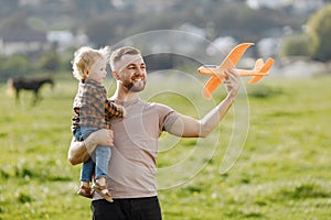 Father and son playing with a plane toy on summer outdoors