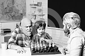 Father and son playing in school class. Happy smiling grandson boy with dad and granddad playing chess. Happy family photo
