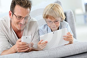 Father and son playing with smartphone and tablet