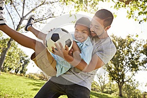 Father And Son Playing Soccer In Park Together