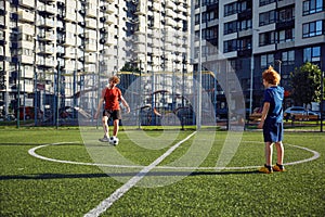 Father and son playing soccer training on football pitch during sunny summer day