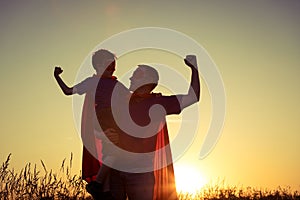 Father and son playing superhero at the sunset time.