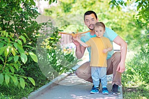 Father and son playing together outdoors in summer day: dad and child are launching toy airplane. New start, parental help concept