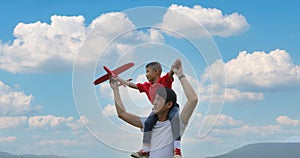 Father and son playing toy airplane on the Meadow at sunset with happy emotion. Family, Holiday and Travel concept