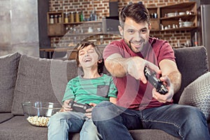 Father and son playing video game at home