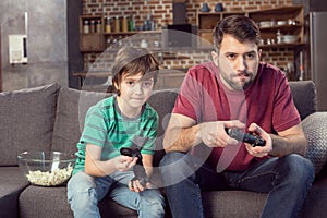 Father and son playing video game at home