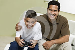 Father with Son Playing Video Game on sofa in living room portrait