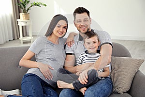 Father, son and pregnant mother spending time together on sofa. Family time