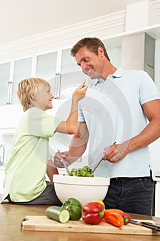Father & Son Preparing Salad In Modern Kitchen