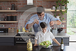 Father and son preparing vegetable salad in kitchen