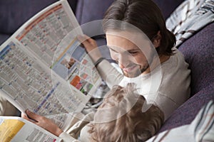 Father and son reading newspapers together at home