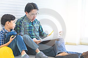 Father Son reading renovation plan in construction industry home repairing. For Family and parenting bonding connection