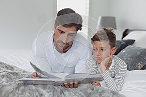 Father and son reading a story book in bedroom