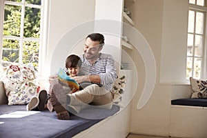 Father And Son Reading Story At Home Together