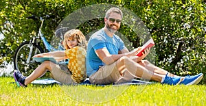 Father and son reading time. Father and son bonding through outdoor reading. Father and son immersed in outdoor reading