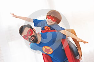 Father and son in the red and blue suits of superheroes. On their faces are masks and they are in raincoats.