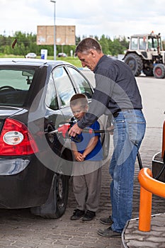 Father with son refueling car on gas station