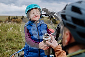 Father and son resting, having snack during hiking together in autumn mountains.