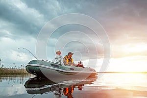 Father and son ride a motor boat on the lake. The concept of family, summer vacation, generation. Copy space