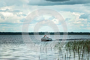 Father and son ride a motor boat on the lake. The concept of family, summer vacation, generation. Copy space