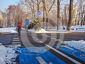 Father and son ride their bicycles along the city bike path on a sunny winter day