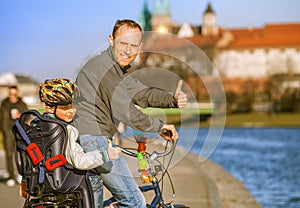 Father & son riding bicycle along river waterfront