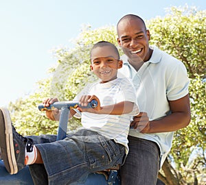 Father and Son Riding On SeeSaw In Park photo