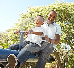 Father and Son Riding On SeeSaw In Park photo