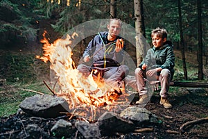 Father and son roast marshmallow on campfire