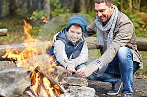 Father and son roasting marshmallow over campfire