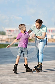 Father and son roller skating on street