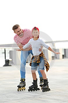 Father and son roller skating on street