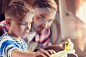 Father and son with ruler measure wood at workshop