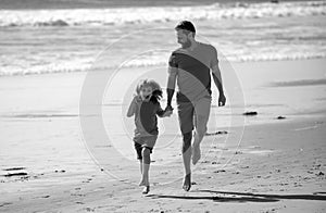 Father and son running on sea. Concept of friendly family and of summer vacation.