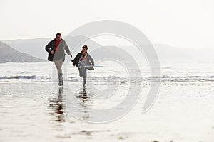 Father And Son Running On Winter Beach With Fishing Net