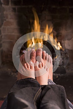 Father and son's feet warming at a fireplace