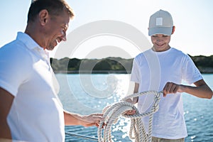 Father and son sailing on the yacht on a sunny day