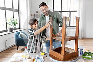 father and son sanding old table with sponge