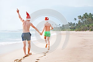 Father and son in Santa`s hats run on perfect sand beach on trop