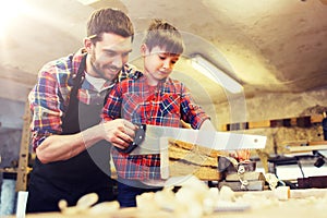 Father and son with saw working at workshop