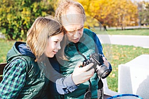 A father and son of school age with photo camera sitting on bench