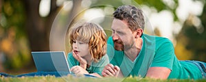 Father and son school boy with laptop. Dad and child use notebook tablet outdoors. Banner for fathers day or father and