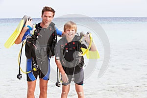 Father And Son With Scuba Diving Equipment On Beach Holiday