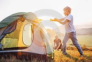 Father and son setting camping tent on the sunset mountain valley