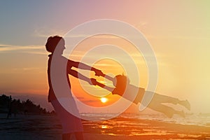 Father and son silhouettes play at sunset