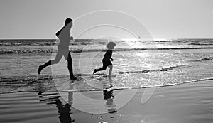 father and son silhouettes running having fun and feel freedom on summer beach, family