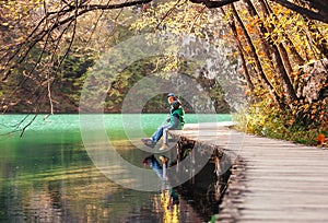 Father with son sit on bridge near the mountain lake, autumn sun