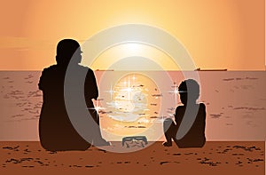 Father and son sitting on the beach, watching sunset